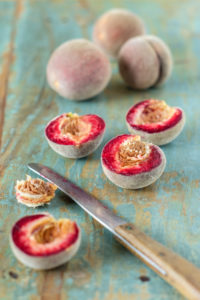 Red vineyard peaches, cut open and uncut, on an old blue wooden table Red vineyard peaches, cut open and uncut, on an old blue wooden table